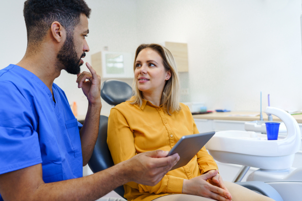 Young woman having consultation with multiracial dentist in his office.