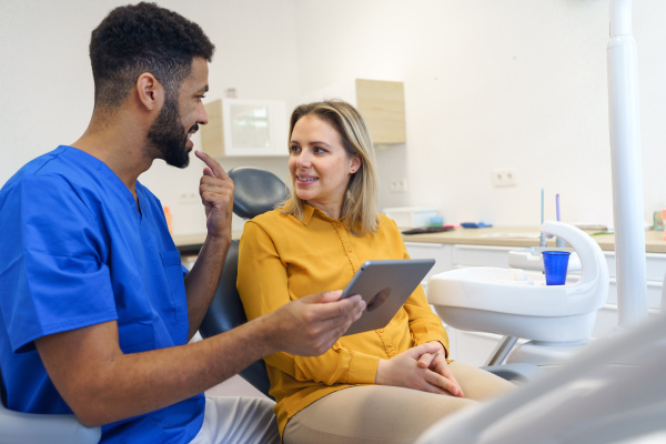 Young woman having consultation with multiracial dentist in his office.