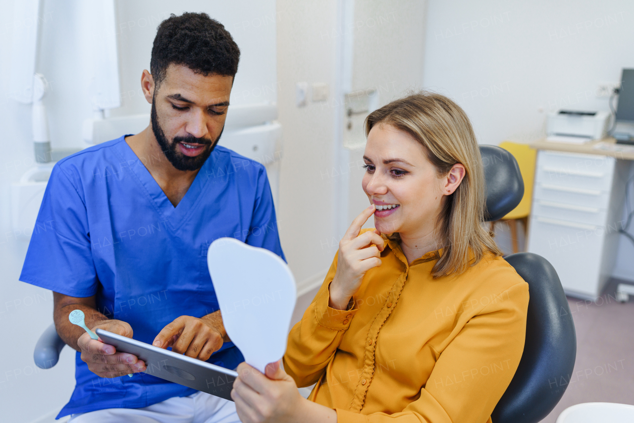 Young woman having consultation with multiracial dentist in his office.