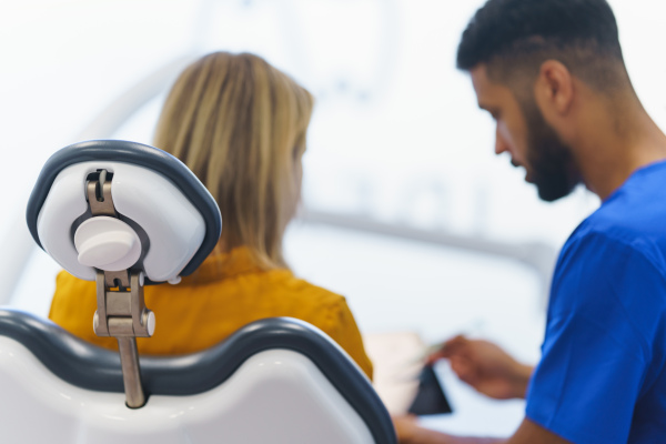 Rear view of multiracial dentist and patient sitting in dentists chair.