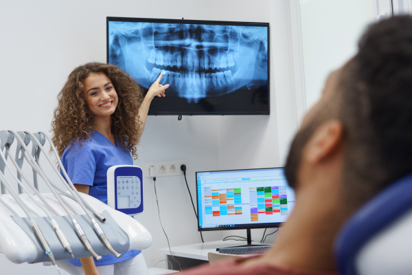 Young dentist showing x-ray image to the patient.