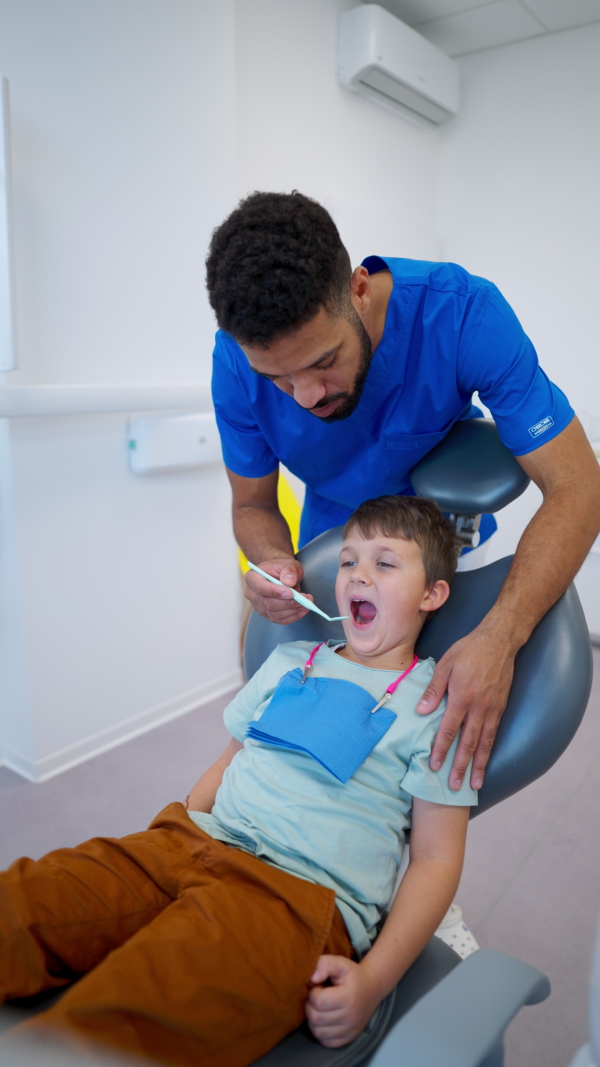 A liitle boy sitting on dentists chair during dentist examination. Vertical footage.