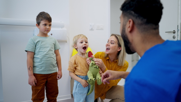 Young multiracial dentist playing with kids at his office in dentist clinic.