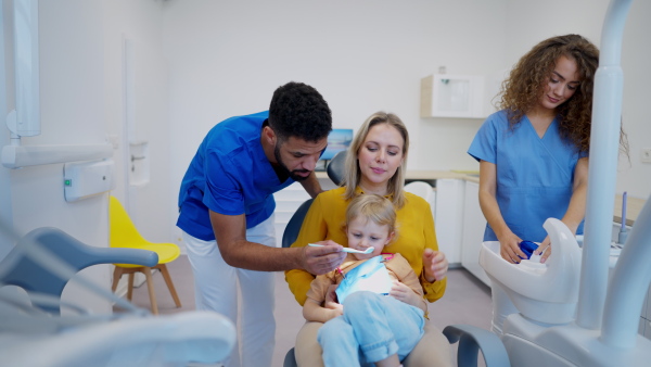 Little girl sitting with her mother on dentist chair, during preventive examination in dental clinic.