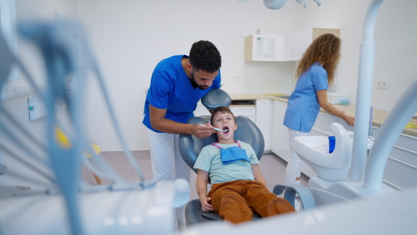 A liitle boy sitting on dentists chair during dentist examination.