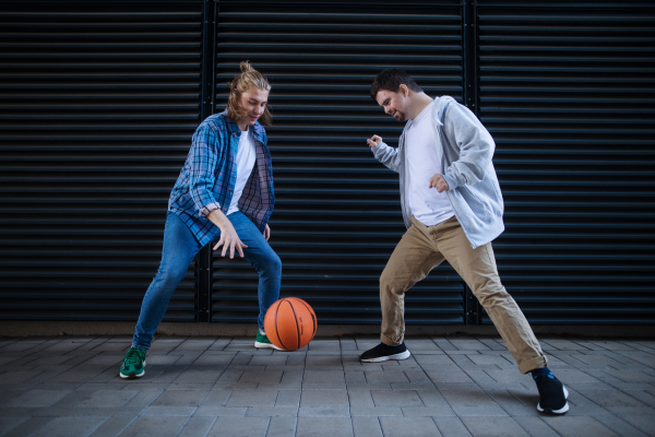 Man with down syndrome playing basketball outdoor with his friend. Concept of friendship and integration people with disability into the society.