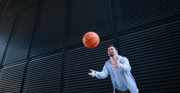 Young man with down syndrom throwing away a basketball ball.