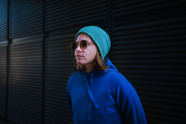 Portrait of young man with cap and sunglasses outdoor in a city. Youth culture.