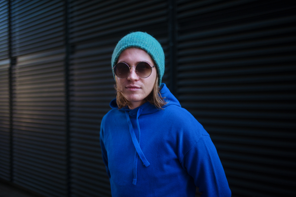 Portrait of young man with cap and sunglasses outdoor in a city. Youth culture.