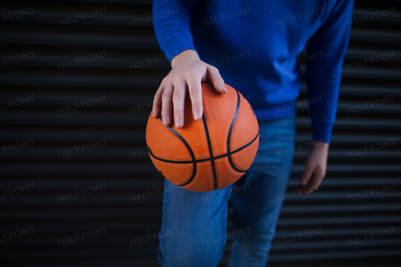 Close-up of young man holding a basketball ball,outdoor in city. Youth culture.