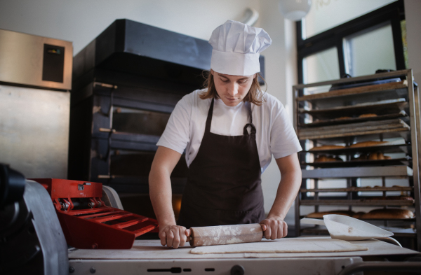 Young baker preparing pastries in a bakery.