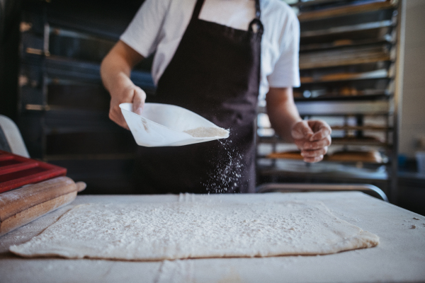 Close-up of young baker preparing pastries in a bakery.