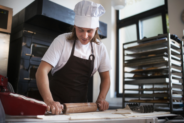 Young baker preparing pastries in a bakery.