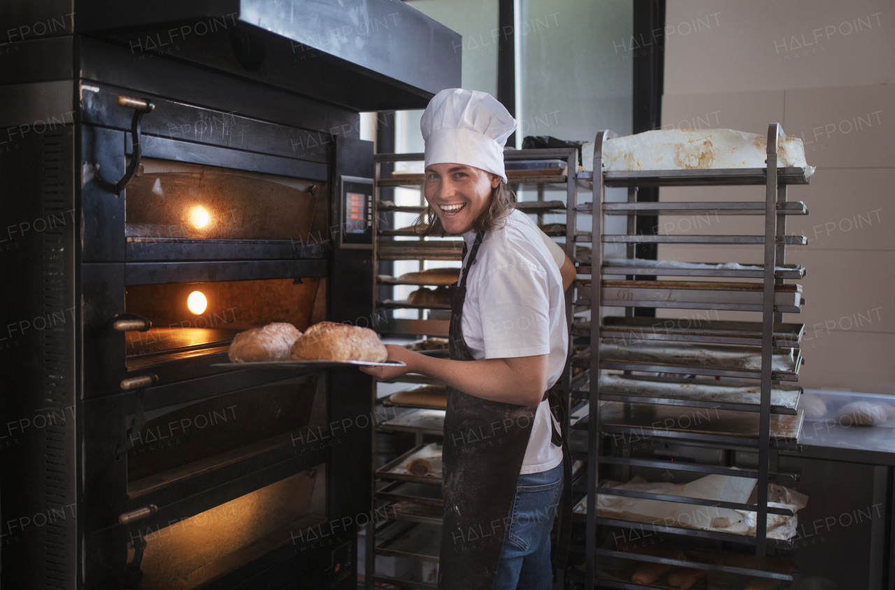 Young baker with chef cap preparing pastries in a bakery.