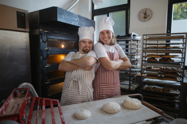 Portrait of man with down syndrom and his colleague in a bakery. Concept of integration people with disability into society.