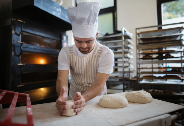 Young baker with down syndrome preparing pastries in bakery. Concept of integration people with a disabilities into society.