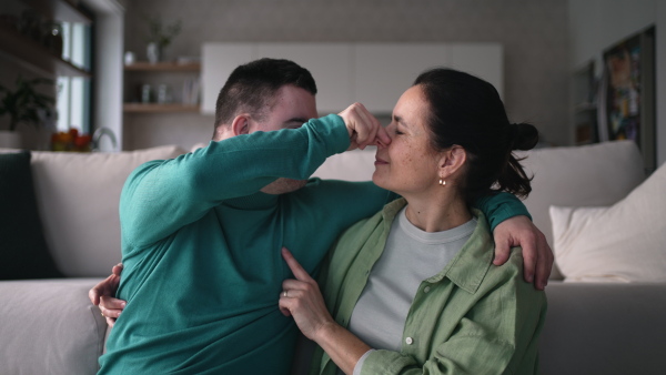 Video of young man with Down syndrome with his mother at home, toasting with juice. Morning routine for man with Down syndrome genetic disorder.