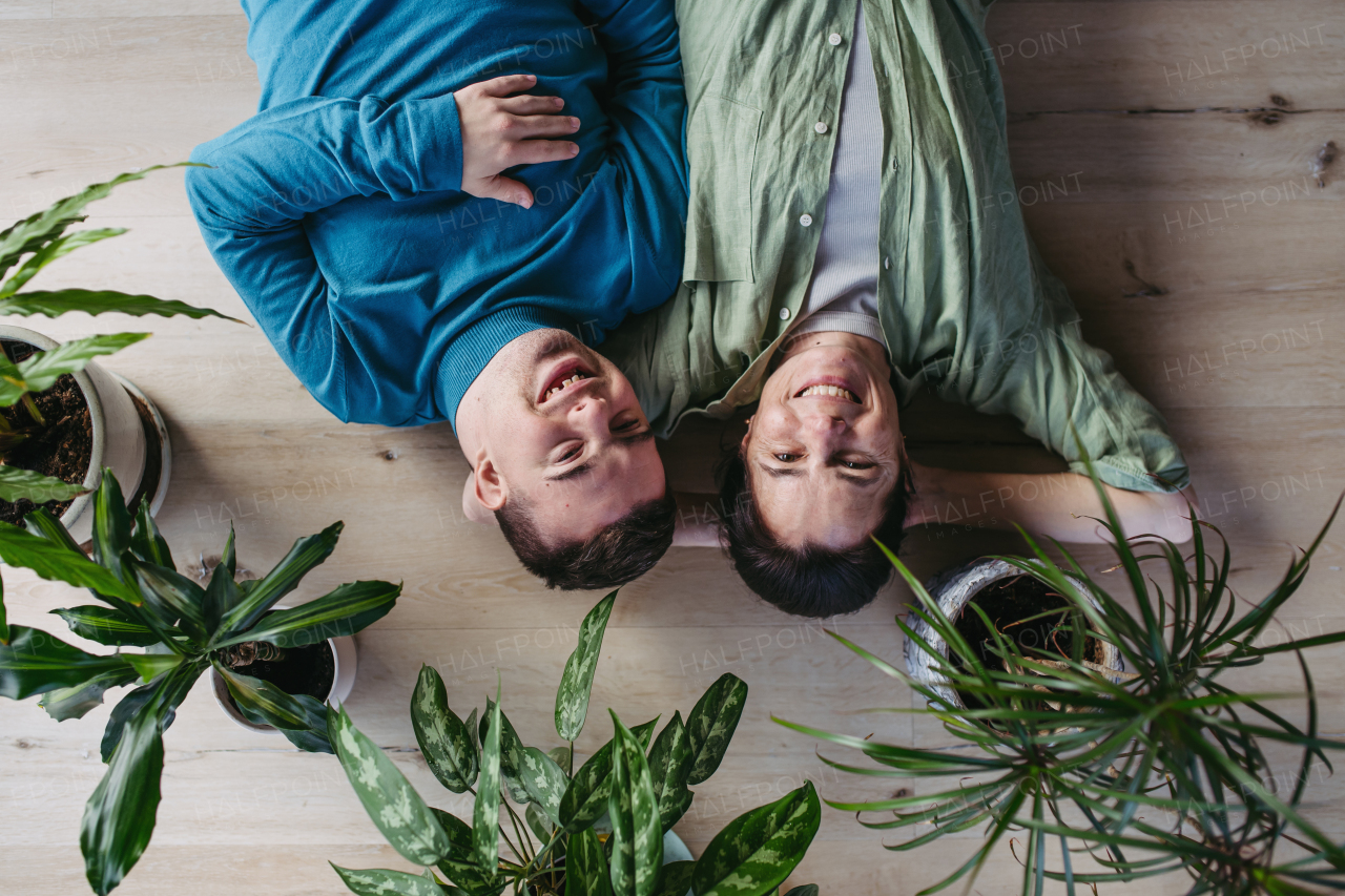 Top view of young man with Down syndrome with his mother at home, lying on floor. Morning routine for man with Down syndrome genetic disorder.