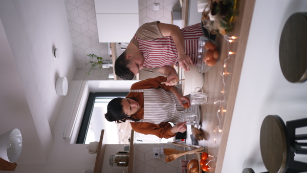 A young man with Down syndrome preparig dough for cookies with his mom at home. Everyday routine for man with Down syndrome.