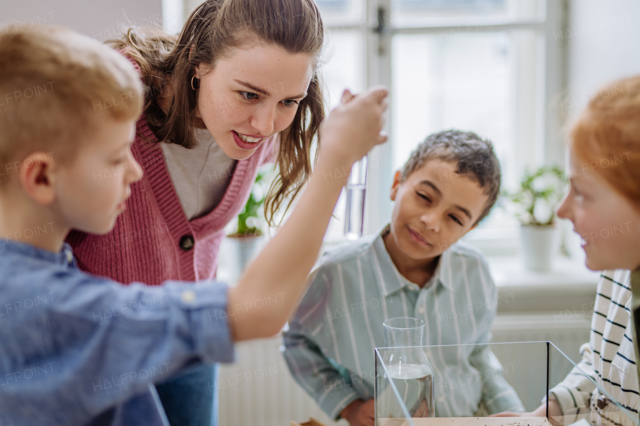 Young teacher making a little greenhouse with their pupils, learning them about planting.