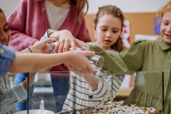 Young teacher making a little greenhouse with their pupils, learning them about planting.