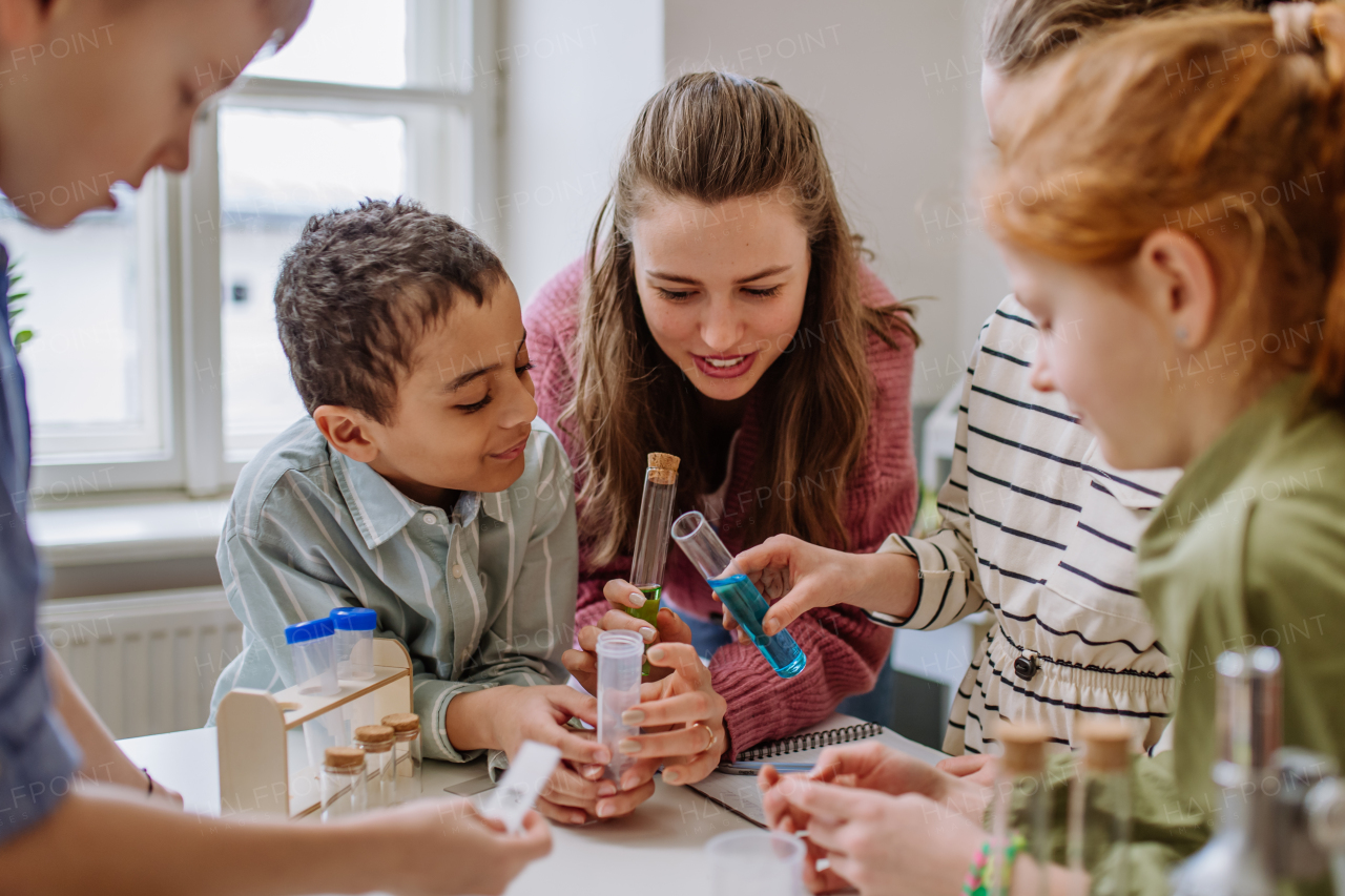 Young teacher doing chemistry experiment with her pupils during science education.