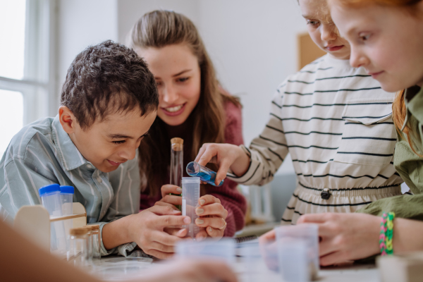 Young teacher doing chemistry experiment with her pupils during science education.