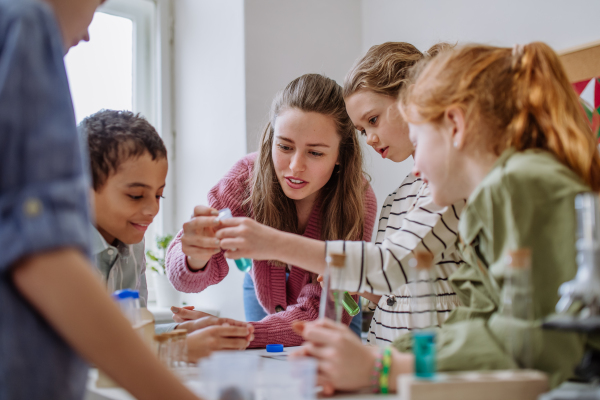 Young teacher doing chemistry experiment with her pupils during science education.