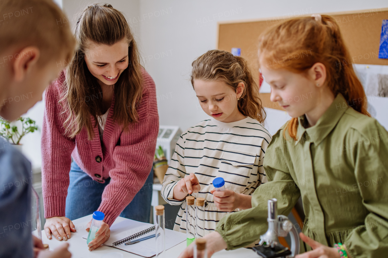 Young teacher doing chemistry experiment with her pupils during science education.