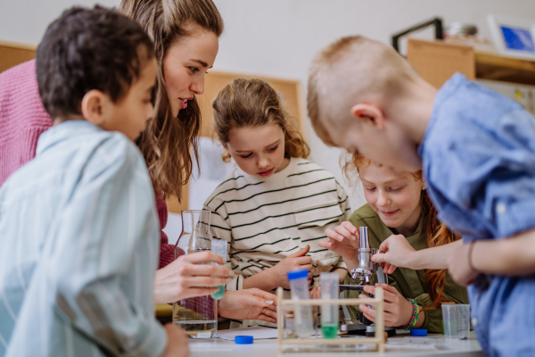 Young teacher doing chemistry experiment with her pupils during science education.