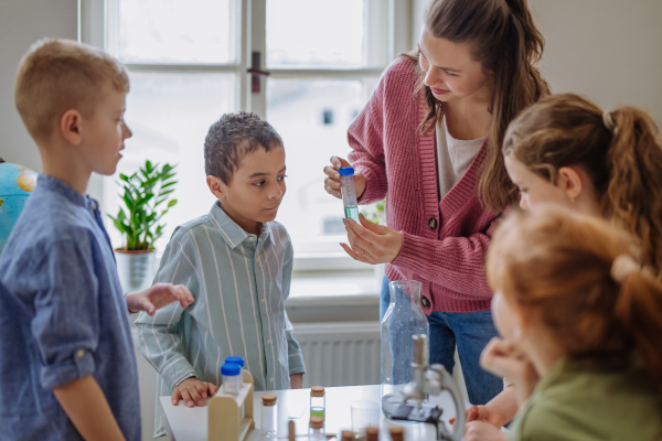 Young teacher doing chemistry experiment with her pupils during science education.