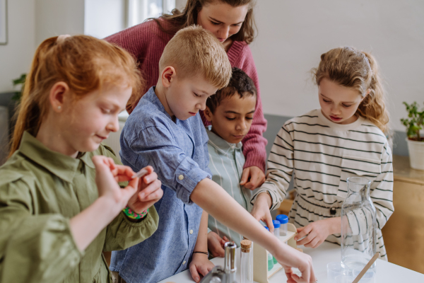 Young teacher doing chemistry experiment with her pupils during science education.