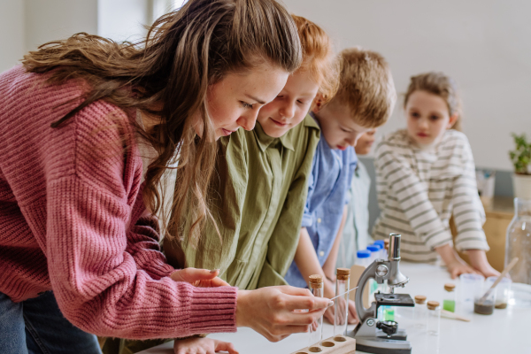 Young teacher doing chemistry experiment with her pupils during science education.