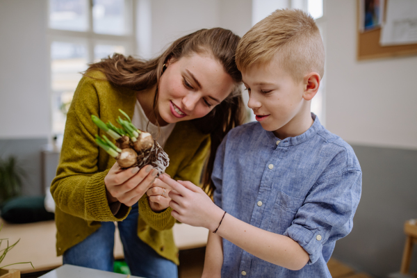 Young teacher learning her pupil how to take care about plants.