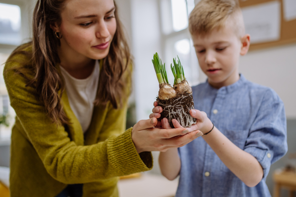 Young teacher learning her pupil how to take care about plants.