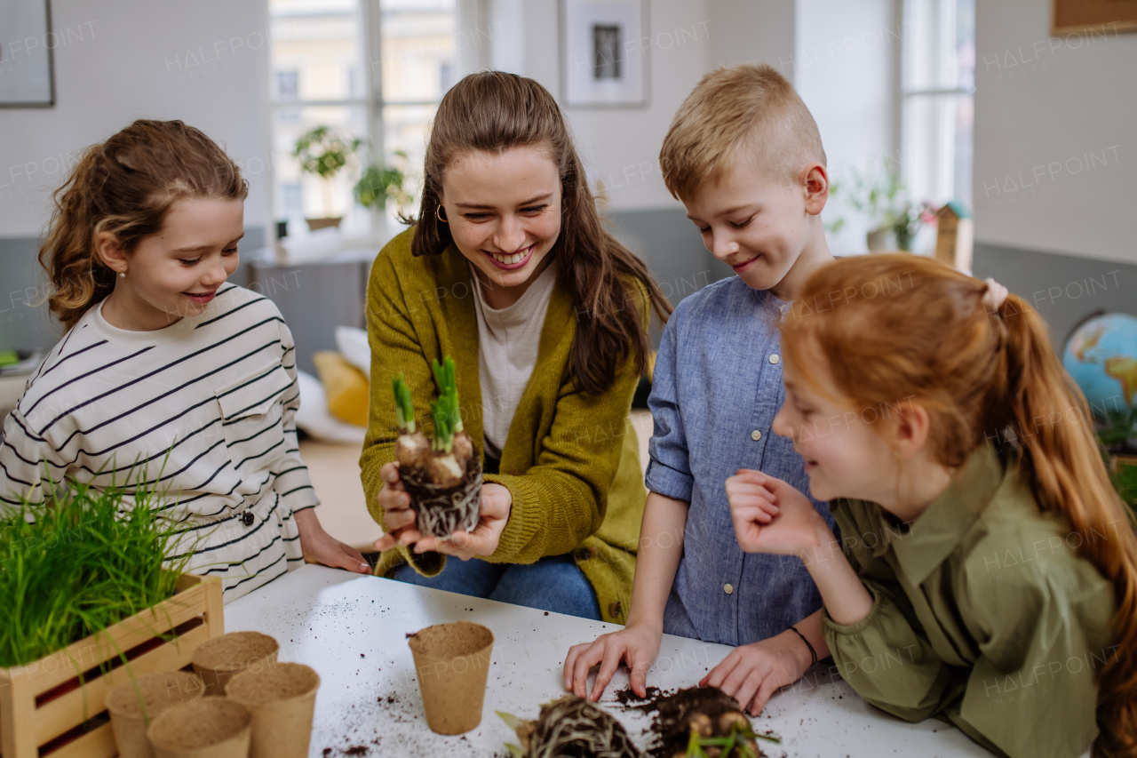 Young teacher learning her pupils how to take care about plants.