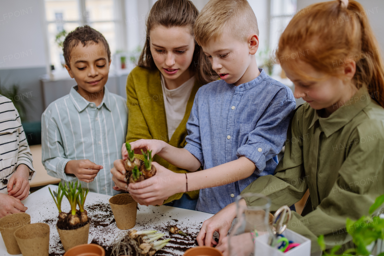 Young teacher learning her pupils how to take care about plants.