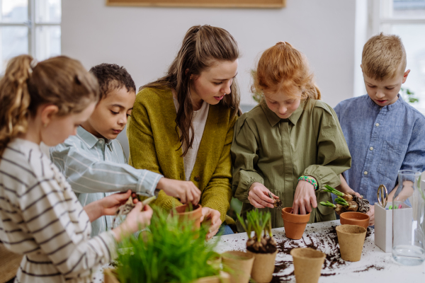 Young teacher learning her pupils how to take care about plants.