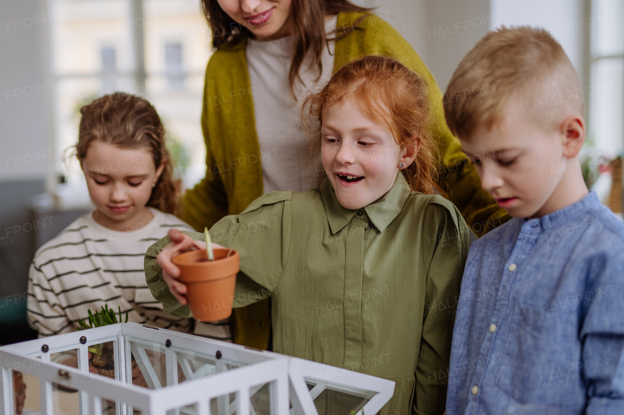 Young teacher learning her pupils how to take care about plants.