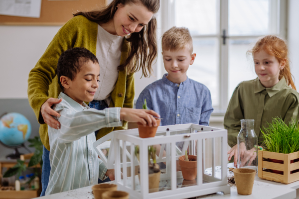 Young teacher learning her pupils how to take care about plants.