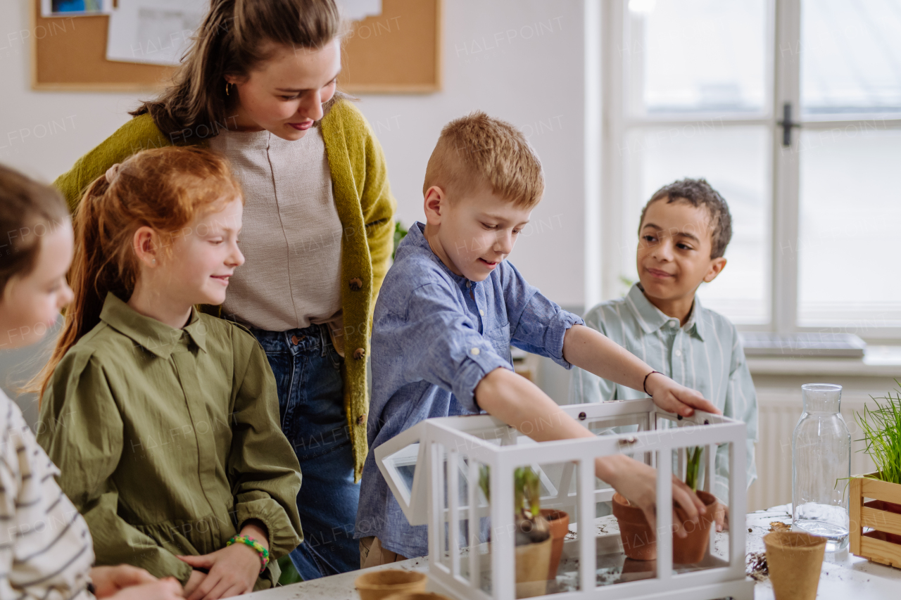 Young teacher learning her pupils how to take care about plants.