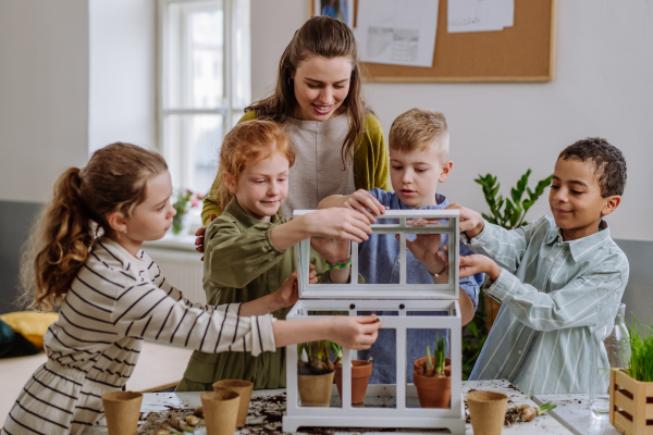 Young teacher learning her pupils how to take care about plants.