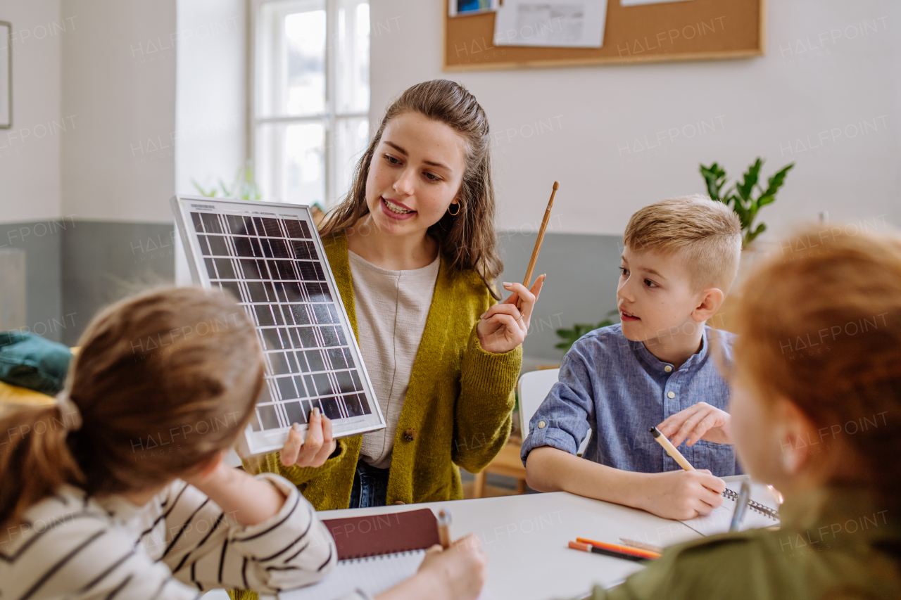 Young teacher with solar panel learning her pupils about solar energy.