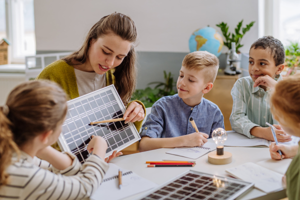 Young teacher with solar panel learning her pupils about solar energy.