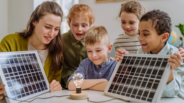 Young teacher with solar panel learning her pupils about solar energy.