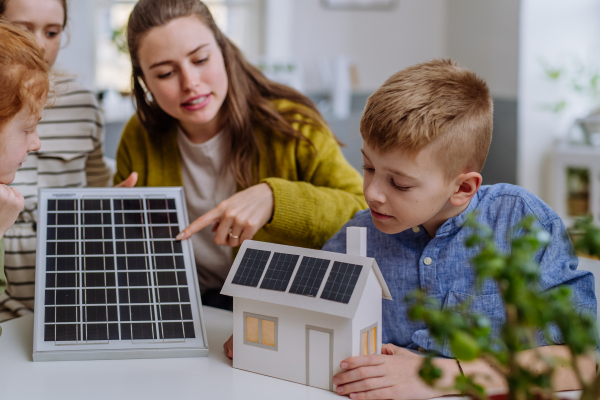 Young teacher with solar panel learning her pupils about solar energy.