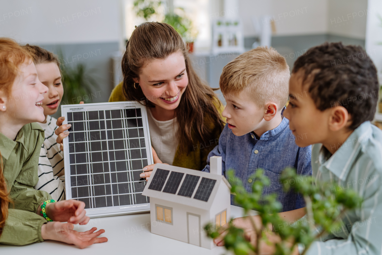 Young teacher with solar panel learning her pupils about solar energy.