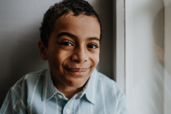 Portrait of multiracial boy sitting near a window.