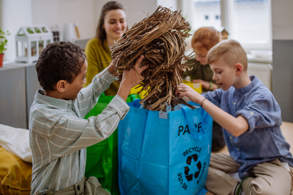 Children and teacher separating rubish in to a bins.