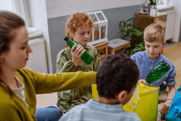 Children and teacher separating rubish in to a bins.